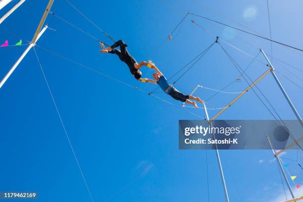 twee trapeze artiesten vliegen in de blauwe hemel - caught in the act stockfoto's en -beelden