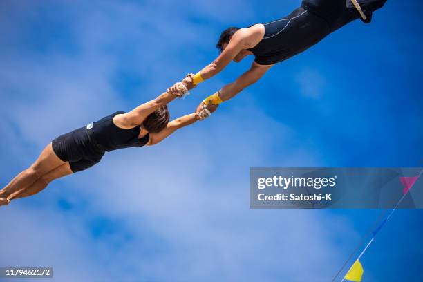 zwei trapezkünstler fliegen gemeinsam am himmel - trapeze stock-fotos und bilder