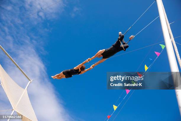 空で一緒に揺れるトラピーズアーティスト - trapeze ストックフォトと画像