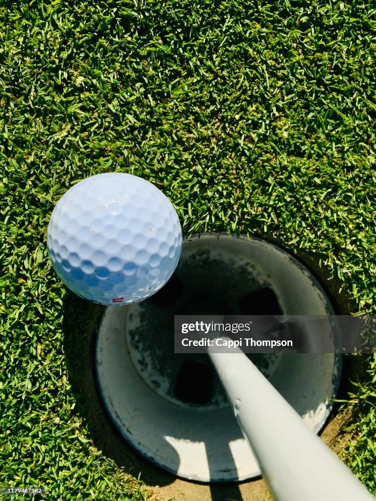 Golf ball on green next to hole
