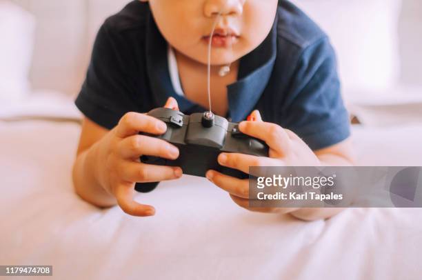a male toddler is playing with a remote control on the bed - remote controlled stock pictures, royalty-free photos & images