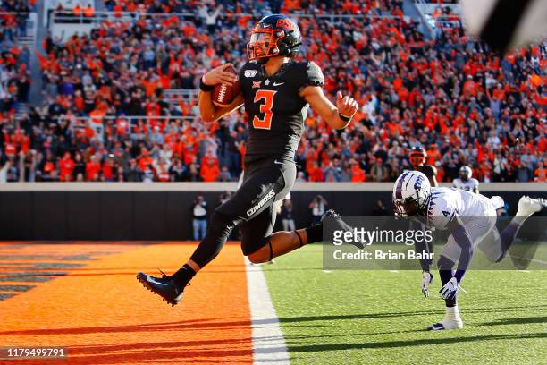 Quarterback Spencer Sanders of the Oklahoma State Cowboys leaps into the end zone for a 43-yard touchdown against safety Keenan Reed of the TCU...