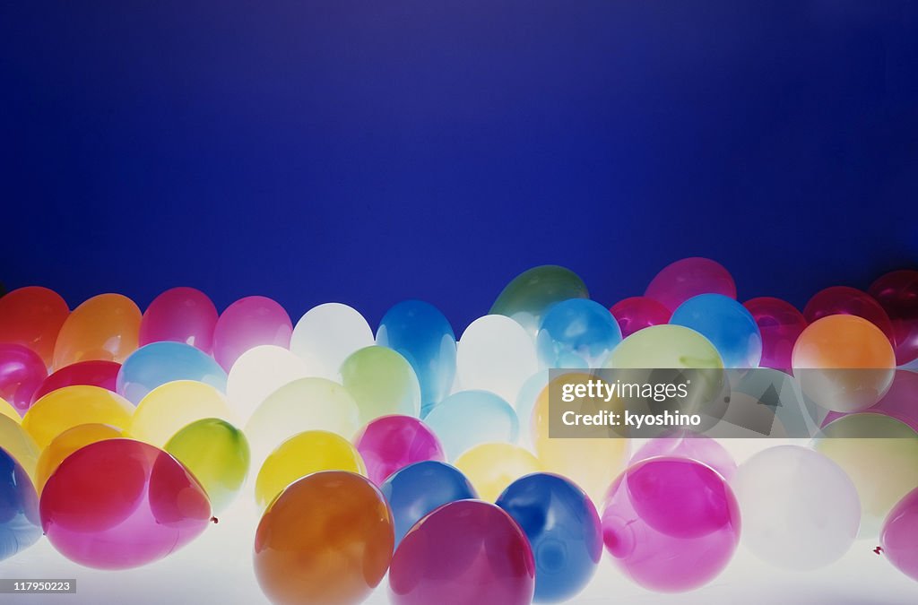 Lots of balloons against blue background with light from bottom