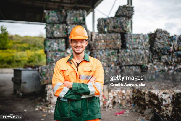 glimlachend werkman buitenshuis bij afvalverwerkings faciliteit - recycling stockfoto's en -beelden