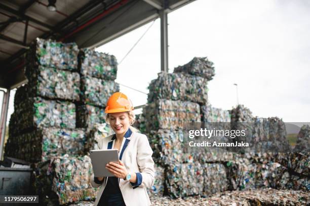 specialista di recupero risorse femminili utilizzando tablet digitale - centro di riciclaggio foto e immagini stock