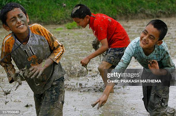 Nepalese children play in the mud as they plant rice in a field on the outskirts of Kathmandu on June 29, 2011. The farmers are celebrating National...