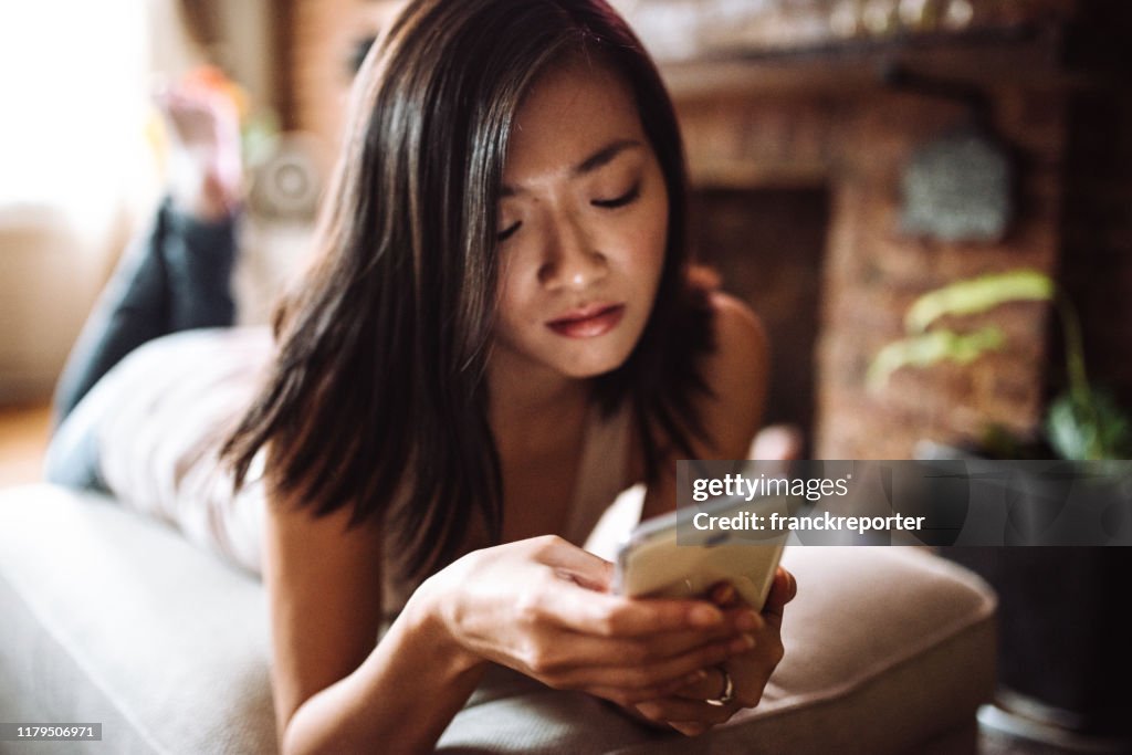 Chinese woman text messaging on the phone at home