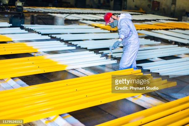 mann malt metall in der fabrik - lackiert stock-fotos und bilder