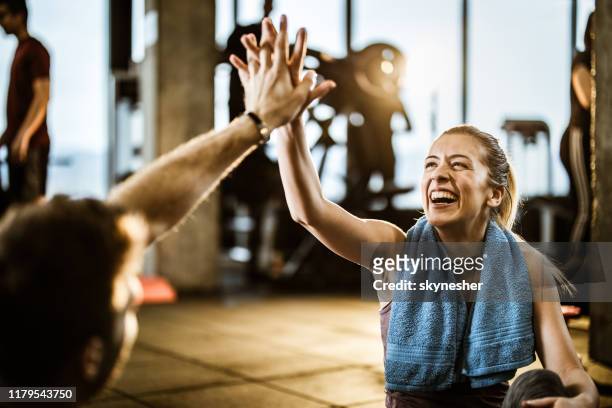 glückliche athletische frau gibt high-five zu ihrem freund auf einer pause in einem fitness-studio. - sports training stock-fotos und bilder