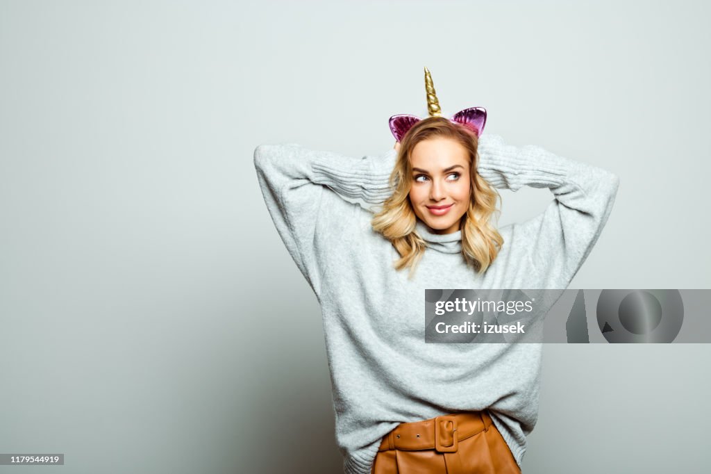 Studio portrait of happy beautiful woman with unicorn headband