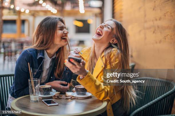 junge damen klatschen im café - smartphone friends stock-fotos und bilder