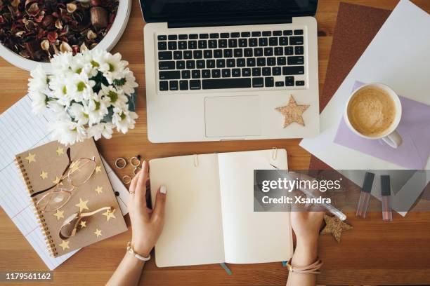 junge frau schreibt notizen und arbeitet an einem laptop - flatlay stock-fotos und bilder