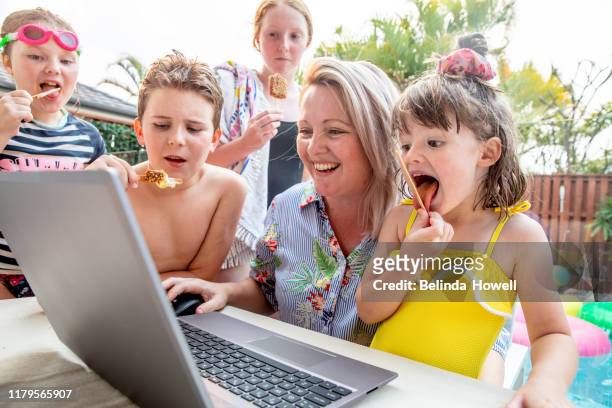 Australian family use a desktop devices together on the back deck whilst eating icecream.