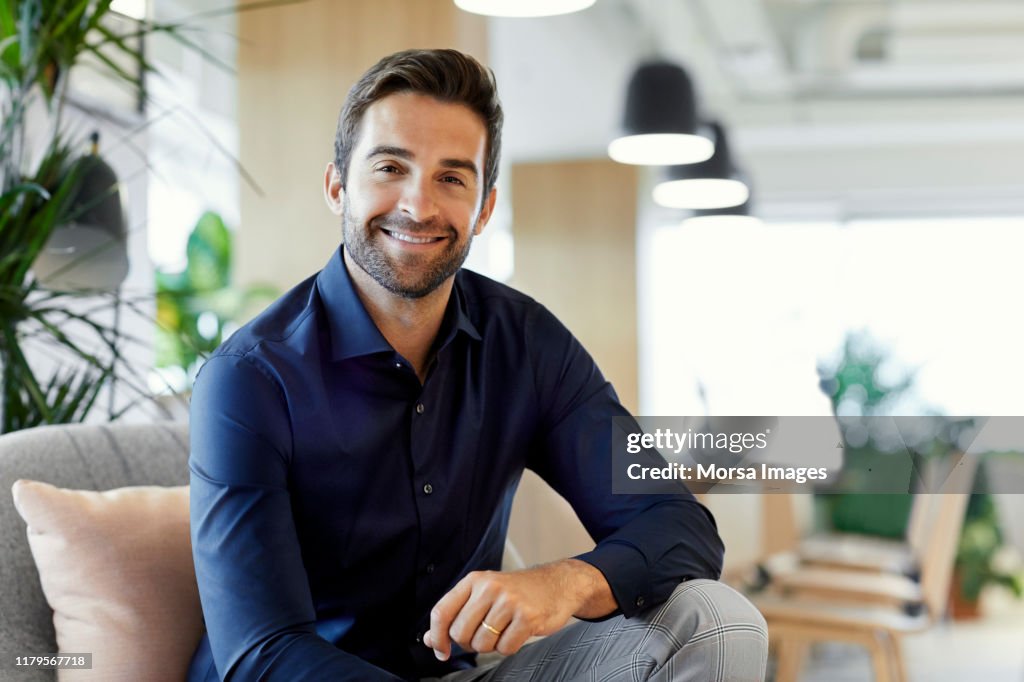 Portrait of happy entrepreneur sitting in office