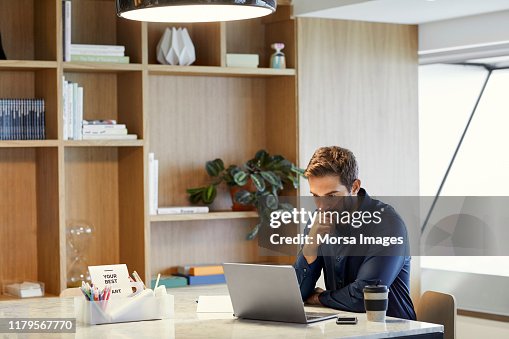Serious businessman using laptop at office desk Serious businessman using laptop at office desk