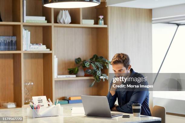 serious businessman using laptop at office desk - contemplation office stock pictures, royalty-free photos & images