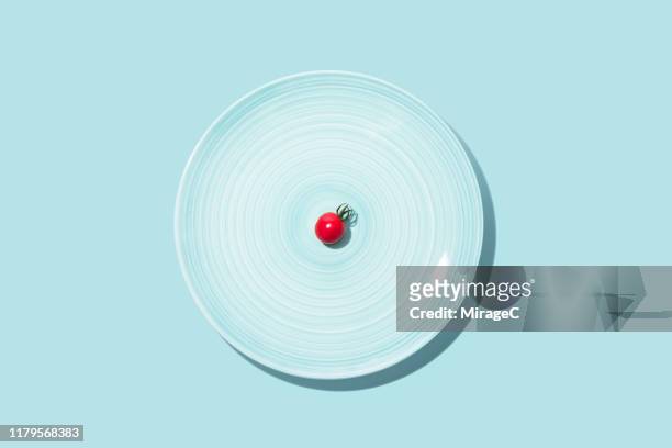 small cherry tomato with big blue plate - simplicity object stock pictures, royalty-free photos & images