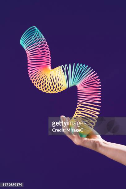 one hand playing with colorful coil toy - metal coil toy stock-fotos und bilder