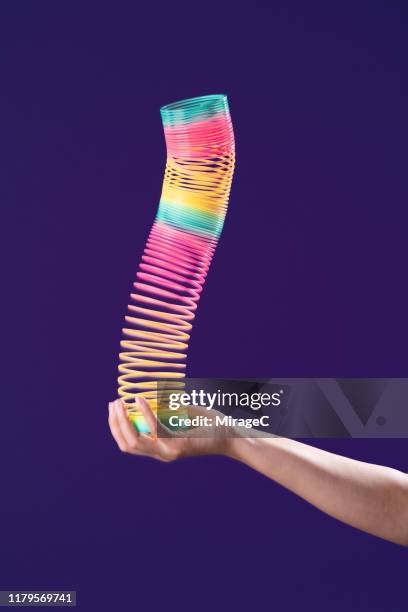 one hand playing with colorful coil toy - metal coil stock pictures, royalty-free photos & images