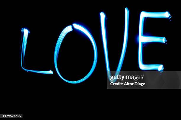 love written with blue light on a black background - lichtspur stock-fotos und bilder