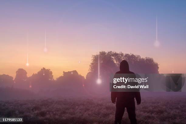 a ufo, supernatural concept. a hooded figure with his back to the camera, looking at lights falling from the sky. across a misty field at sunrise. - star wars stock pictures, royalty-free photos & images