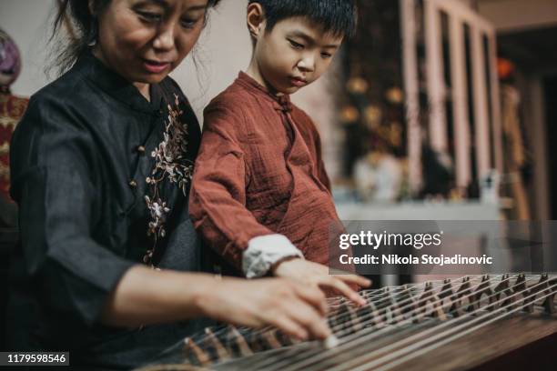 chinese grandmother and grandson in traditional clothes playing harp - chinese harp stock pictures, royalty-free photos & images