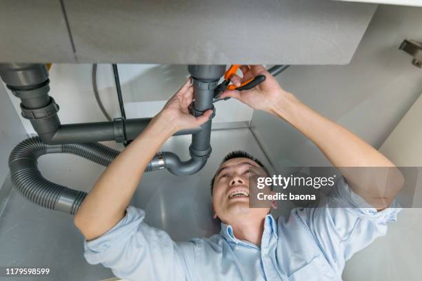 man repairing sink pipe in the kitchen - kitchen straighten stock pictures, royalty-free photos & images