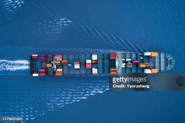 a large container ship is approching the port full loaded with containers and cargo - aerial - top down view - pacific ocean trade stock pictures, royalty-free photos & images