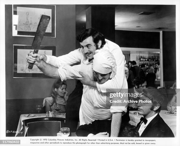 Terry Jones assaulting a cook holding a knife in a restaurant as Graham Chapman looks on in a scene from the film 'And Now for Something Completely...