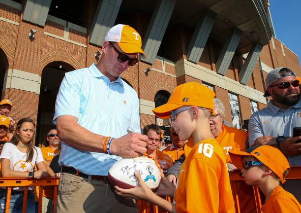 Tennessee Volunteers alumnus Peyton Manning signs a ball for a fan before the Tennessee Volunteers play against the Georgia Bulldogs at Neyland...