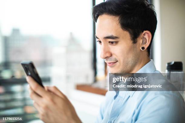 hearing impaired man reading e-mail on phone - hearing aids stock pictures, royalty-free photos & images