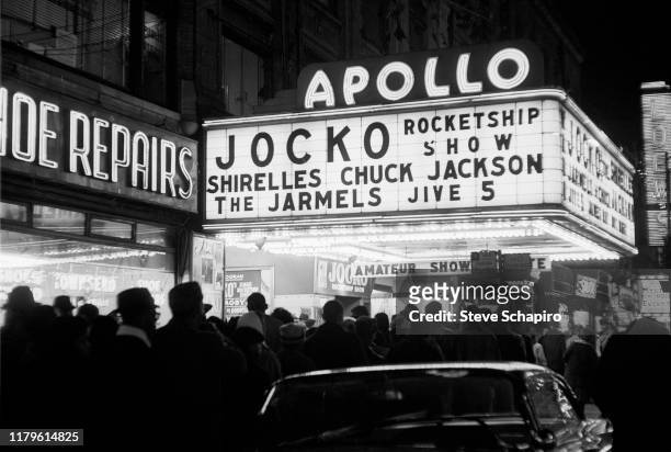 Nighttime view of a crowd lined up outside the Apollo Theater , New York, New York, 1961. The marquee advertises performances by the Jocko Rocketship...