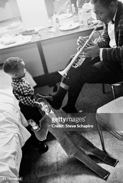 An unidentified musician plays trumpet for a small boy backstage at the Apollo Theater, New York, New York, 1961. The boy holds a cutout photograph...