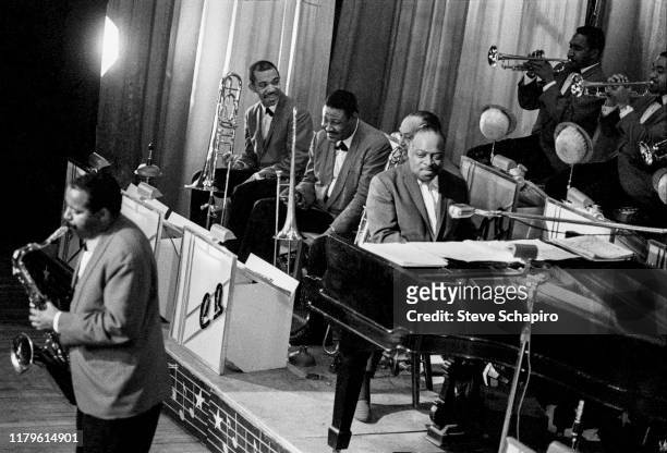 American Jazz musician and bandleader Count Basie plays piano as he performs onstage with the Count Basie Orchestra at the Apollo Theater, New York,...