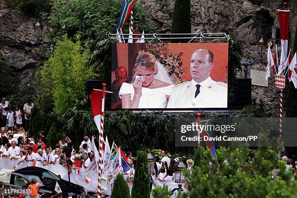 Princess Charlene of Monaco and Prince Albert II of Monaco appear on a video screen as they visit Sainte Devote church during their religious wedding...