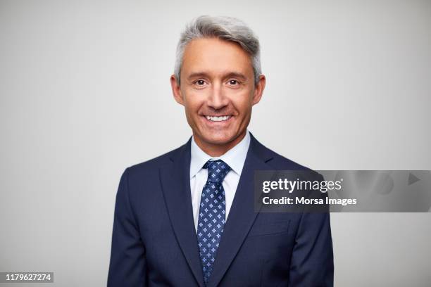 smiling mature male leader wearing navy blue suit - chef on white stock-fotos und bilder