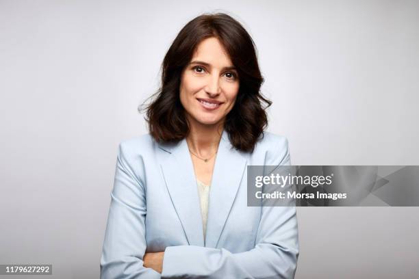 smiling mid adult businesswoman with arms crossed - fashion director fotografías e imágenes de stock