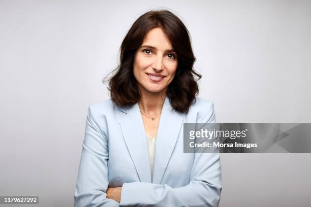 smiling mid adult businesswoman with arms crossed - blue blazer stock pictures, royalty-free photos & images