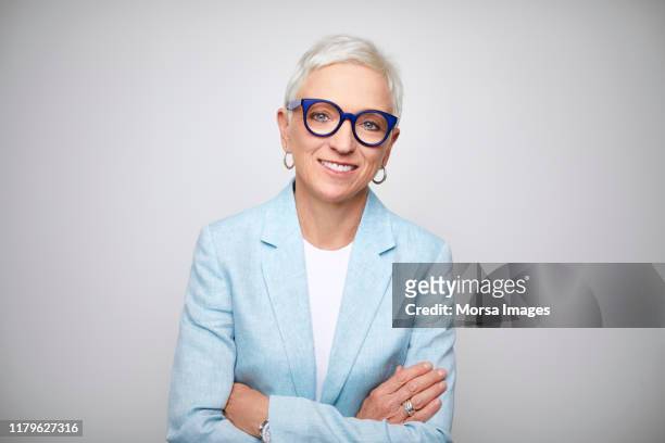 mature businesswoman standing with arms crossed - chief executive officer foto e immagini stock