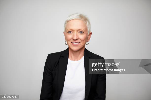 smiling mature businesswoman wearing black blazer - portrait white hair studio stock pictures, royalty-free photos & images