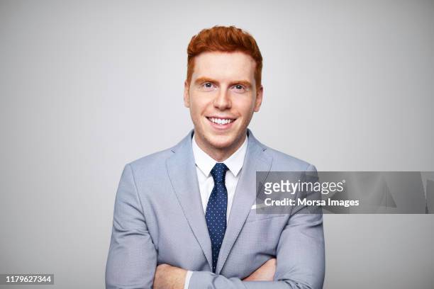 smiling redhead businessman with arms crossed - pelirrojo fotografías e imágenes de stock