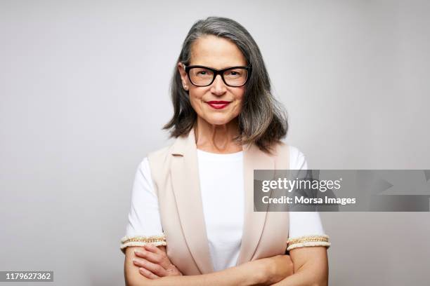 mature female ceo with arms crossed - portrait photos et images de collection