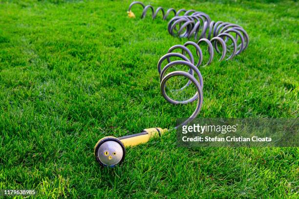 garden spray nozzle attached to a spring hose on grass - wet hose ストックフォトと画像