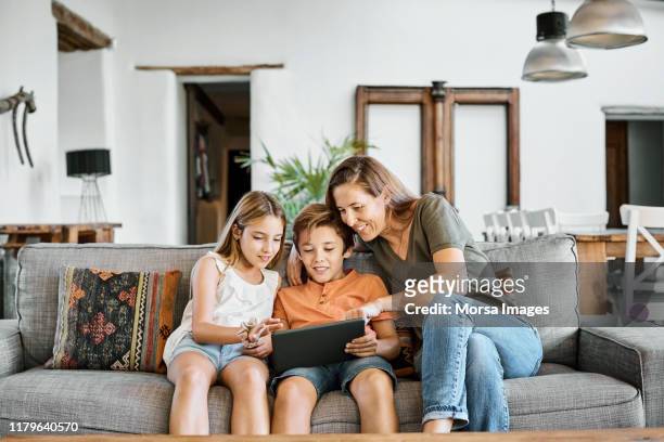mother showing digital tablet to children at home - girls of spain stock pictures, royalty-free photos & images