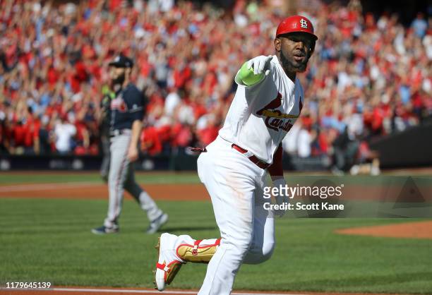 Marcell Ozuna of the St. Louis Cardinals celebrates as he rounds first base after his solo home run as Dallas Keuchel of the Atlanta Braves reacts...