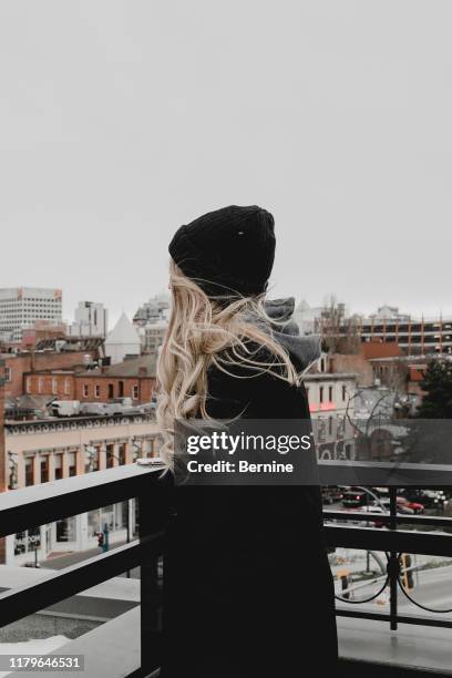 young woman on rooftop facing city - traditionele koksmuts stockfoto's en -beelden