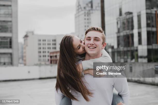 adorable young couple kissing on cheek - teenage couple stock pictures, royalty-free photos & images