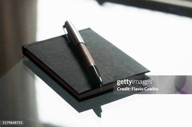 fountain pen and notebook left on glass table - fountain pen stockfoto's en -beelden