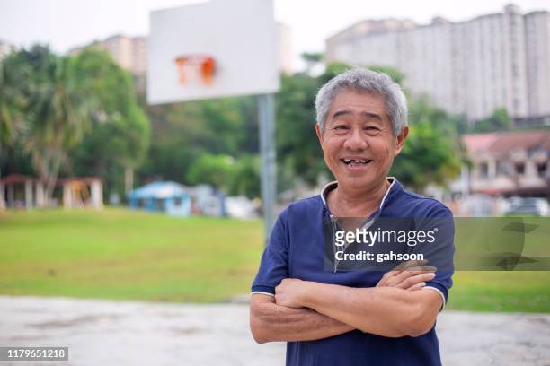 smiling senior asian man standing in basketball court - skill gap stock pictures, royalty-free photos & images