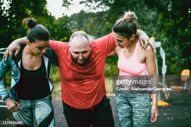 females helping hurt friend after training - fat man lying down stock pictures, royalty-free photos & images